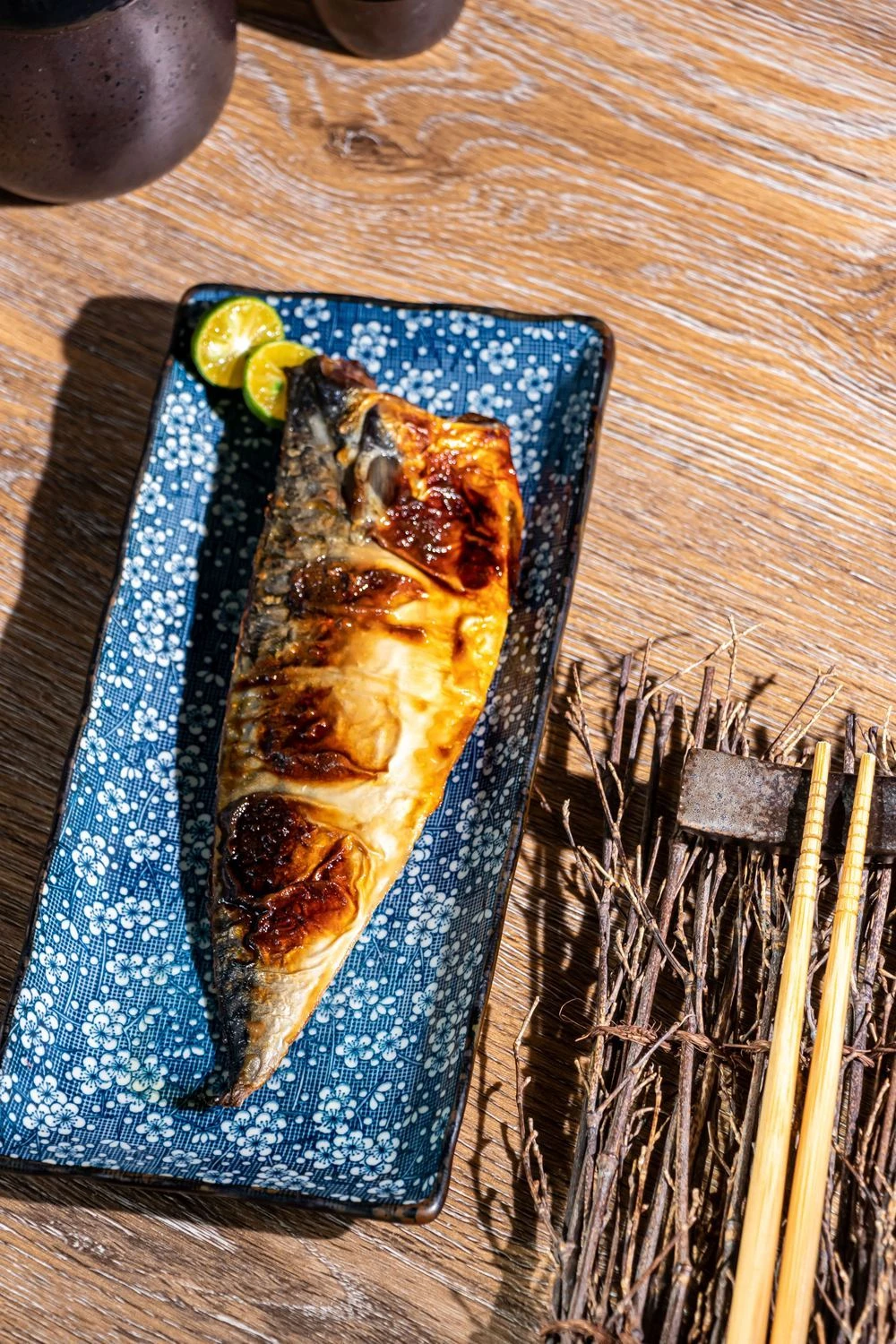 日式餐桌上的烤鯖魚，搭配檸檬與餐具