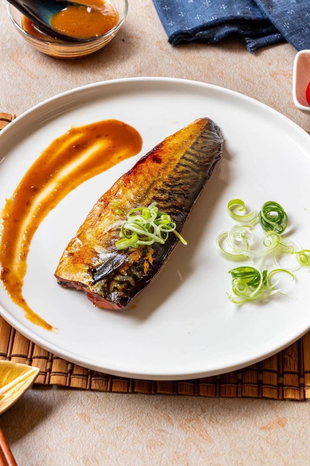 鯖魚料理擺盤，搭配醬汁與蔥絲