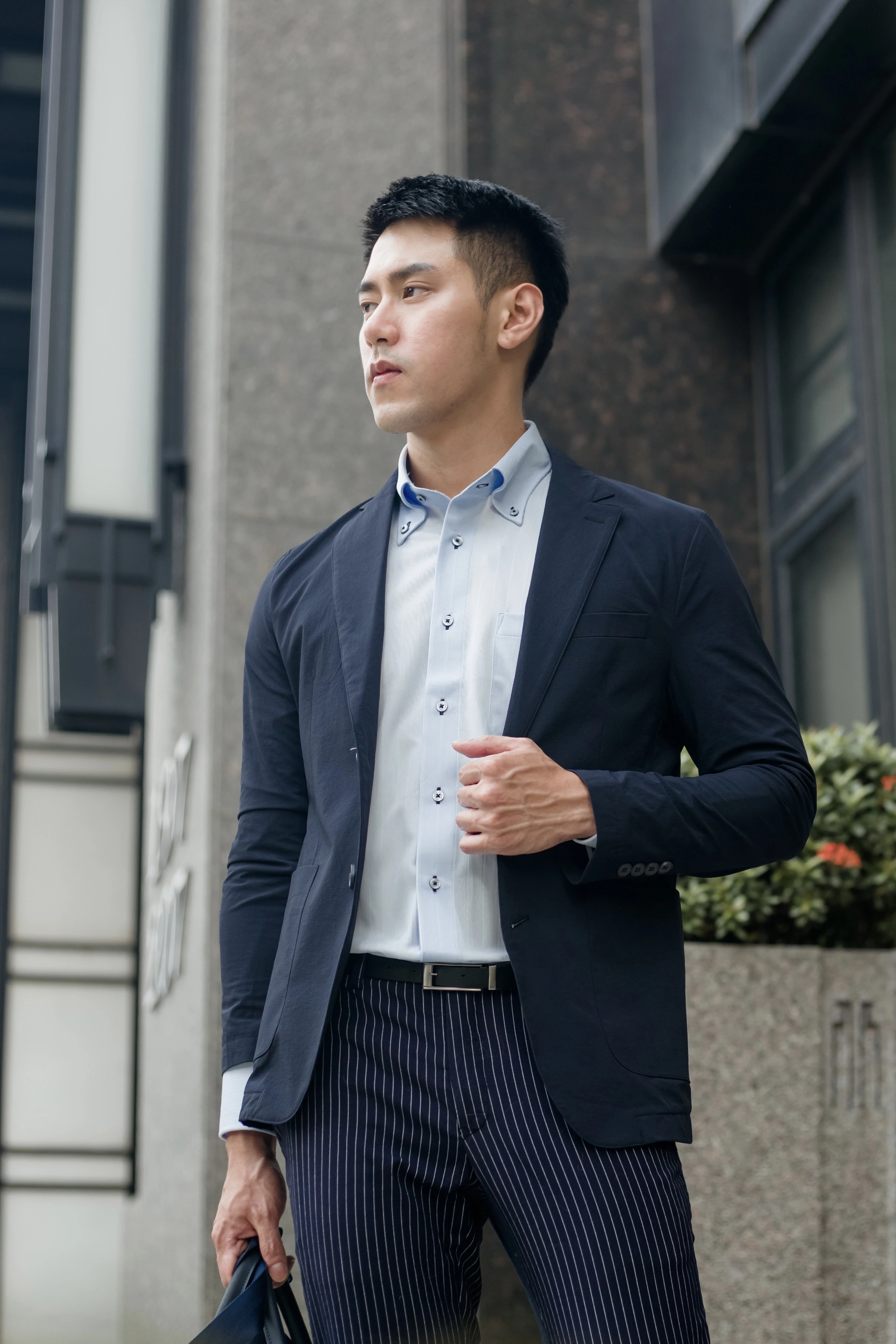 男子身穿深藍色休閒西裝外套、淺藍色襯衫與深藍白色直條紋西裝褲,展現都會商務休閒風格。